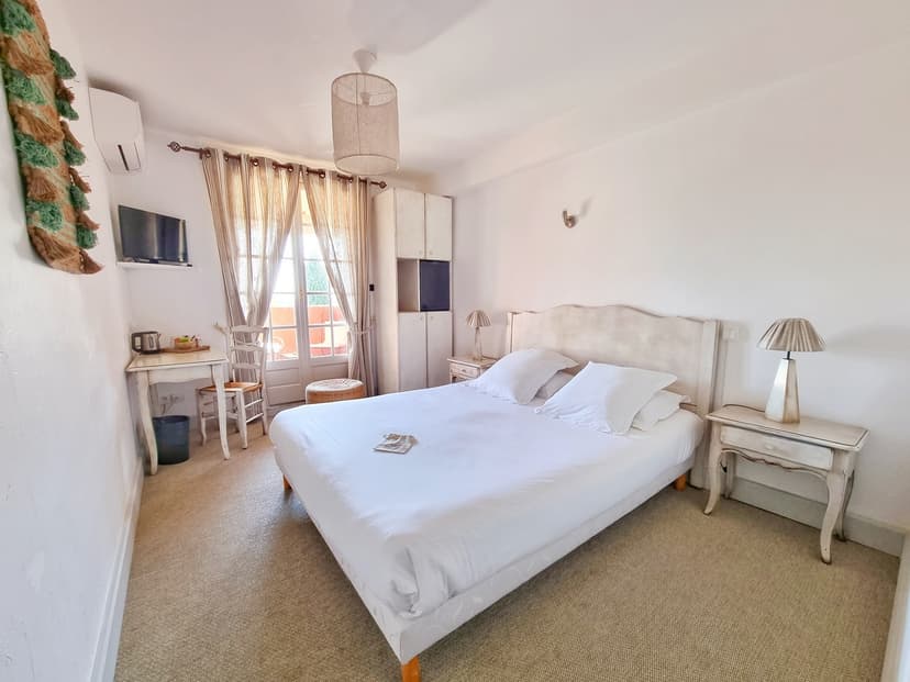 Bright bedroom in Castillon-Des-Baux with white linens, light furniture, and balcony access.