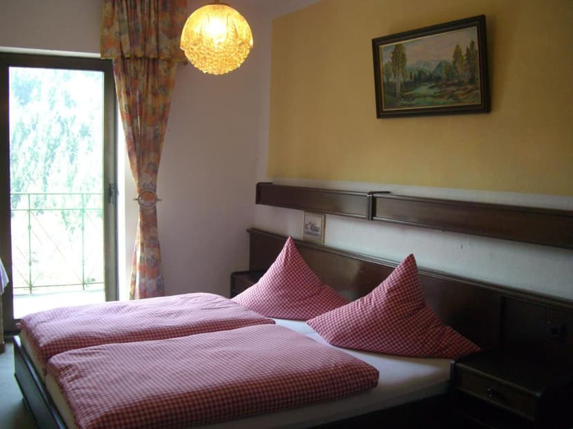 Hotel room with twin beds, red gingham bedding, and balcony door at Hotel Restaurant Burg Ramstein.