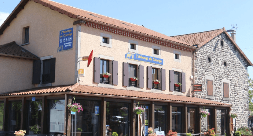 L'Auberge du Couvige hotel and restaurant with stone and stucco facade under blue sky.