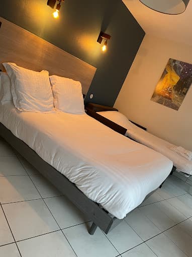 Hotel room with a made bed, wooden headboard, and warm lighting, likely in Hôtel du Languedoc.