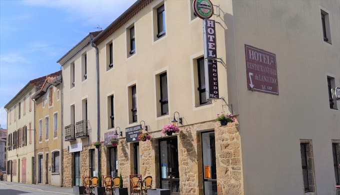 Hotel du Languedoc building with stone base, outdoor seating, and Heineken sign on a sunny street.