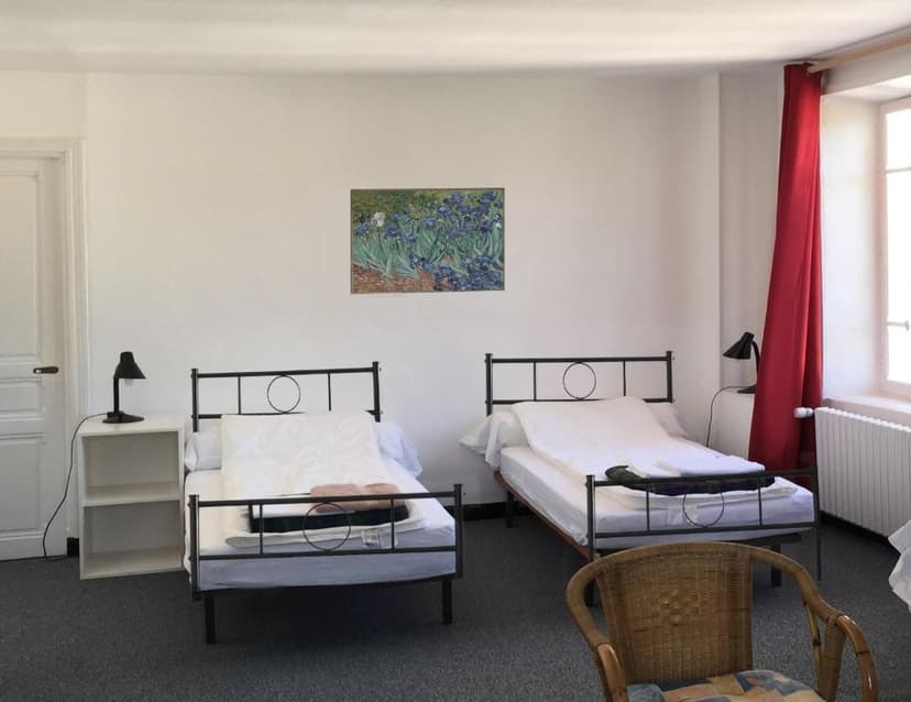 Twin beds in white room with Van Gogh print and red curtain by window