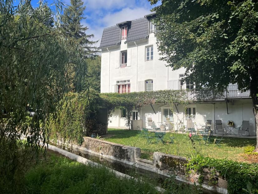 White guesthouse with garden seating next to a narrow water channel, L'Etoile.