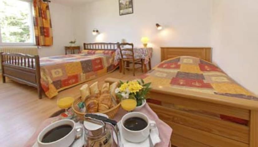 Hotel room with two wooden beds, breakfast tray with coffee and croissants, and yellow flowers.