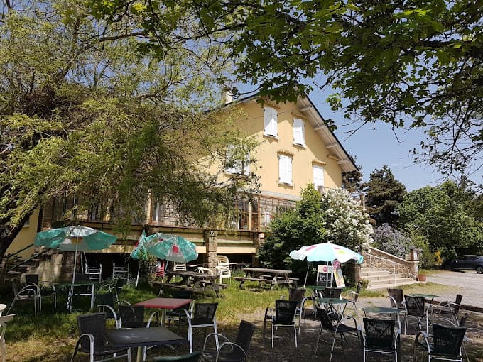 Outdoor seating area with tables and umbrellas in front of a yellow hotel building.