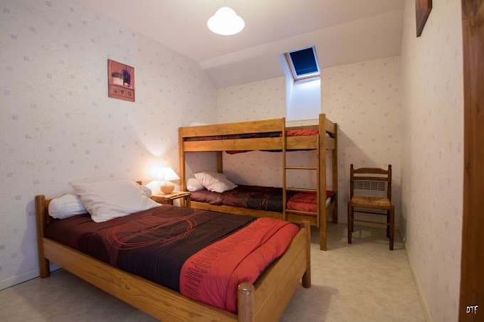 Bedroom with wooden single bed, wooden bunk beds, and a skylight, in Gîte Le Fournil de Sagnabous.