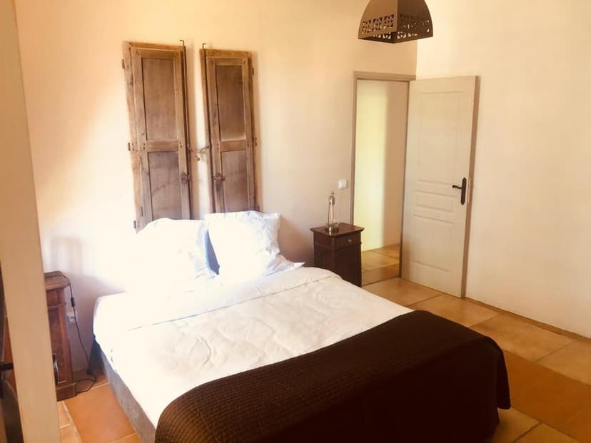 Bedroom with white bedding, rustic wooden shutters, and terracotta tile floor at Le Château de Cambiaire.