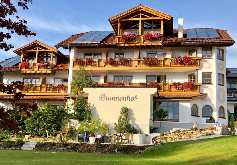 Hotel Brunnenhof building with wooden balconies, flower boxes, and solar panels on the roof.