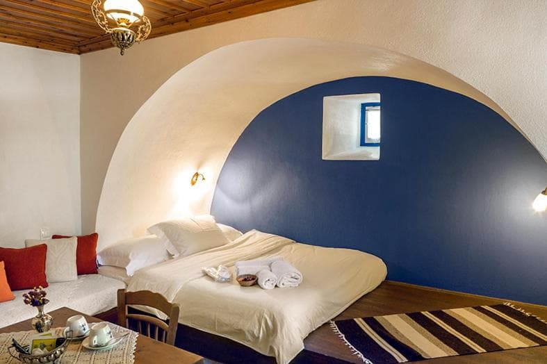 Bedroom with arched alcove, white bedding, and dark blue accent wall, Saxonis Houses & Villa.