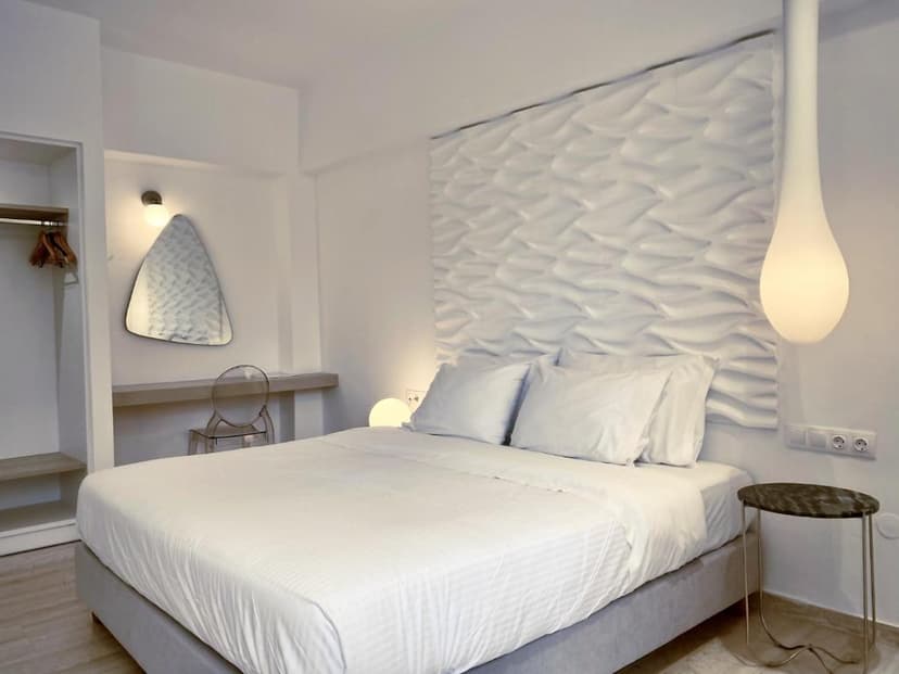Modern white hotel bedroom with textured headboard, large bed, and unique pendant light