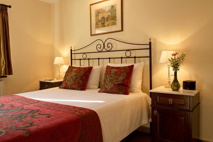 Bedroom in The Merchant's House with wrought iron bed, red pillows, and bedside lamps