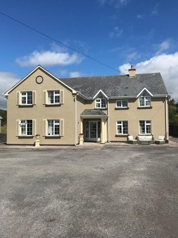 Kielty's of Kerry Bed and Breakfast exterior with beige stucco and slate roof under blue sky.
