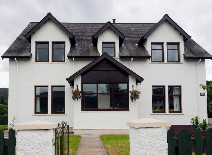 White House B&B with white stucco exterior and dark trim under cloudy sky.