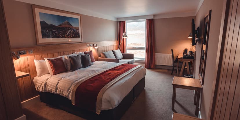 Hotel bedroom with large bed, wooden accents, and view of barren landscape through window