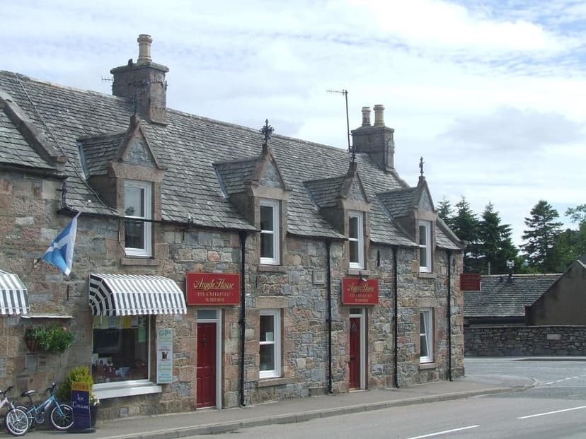 Argyle House B&B with stone facade, Scottish flag, and striped awnings by road