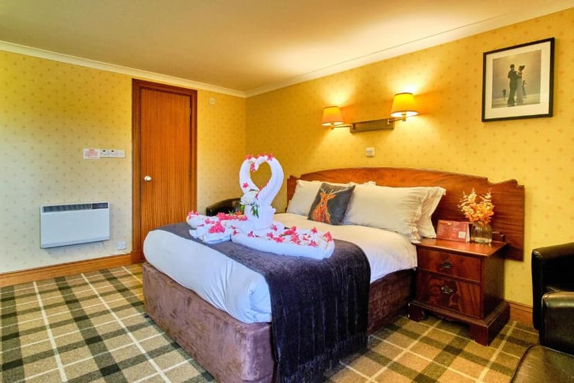 Hotel bedroom with towel swans, flower petals, and tartan carpet, likely Muthu Ben Doran Hotel.