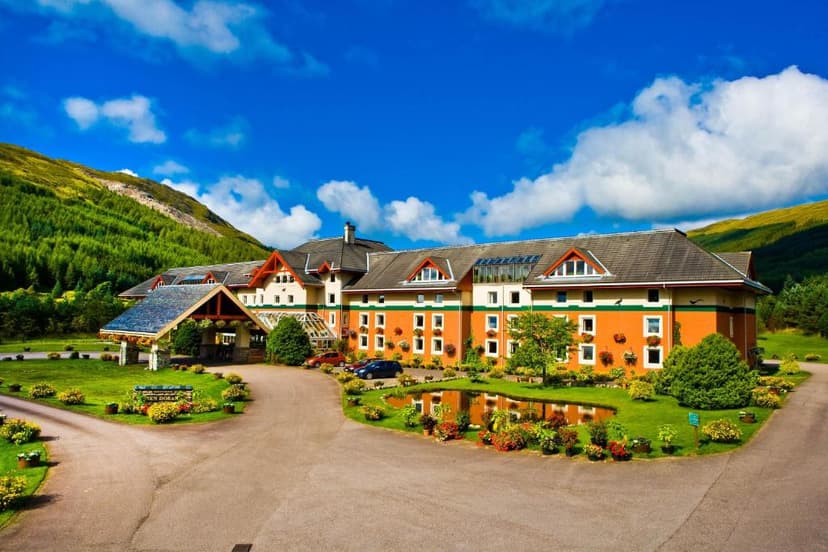 Muthu Ben Doran Hotel entrance with pond and green mountains under blue sky.