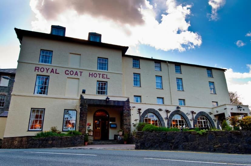 Royal Goat Hotel building facade with stone entrance and arched windows under a cloudy blue sky.
