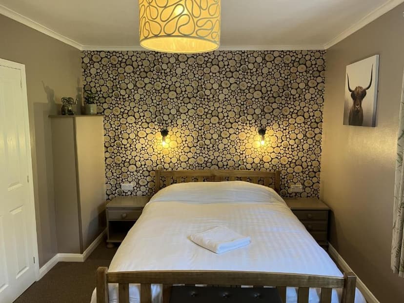 Bedroom with wood slice accent wall, wooden bed frame, and Highland cow artwork.