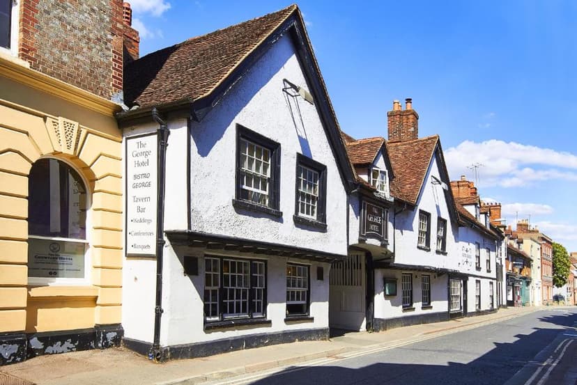 The George Hotel, a historic white building with black trim, on a sunny street.