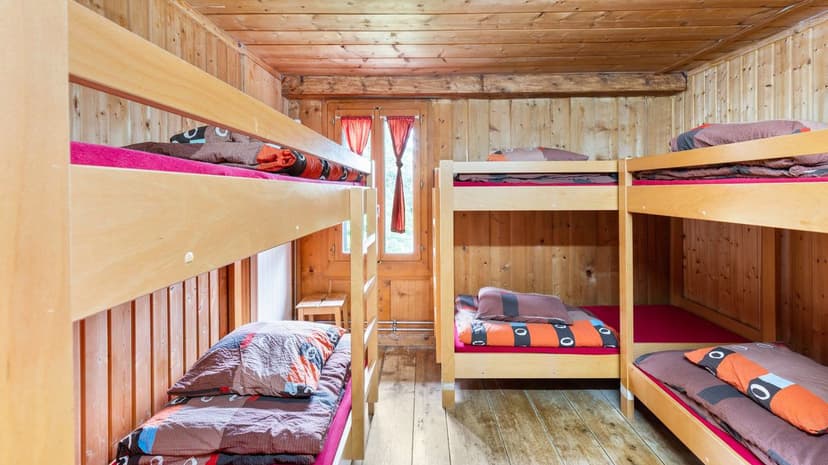 Wooden bunk beds with colorful bedding inside a rustic room with wood-paneled walls.