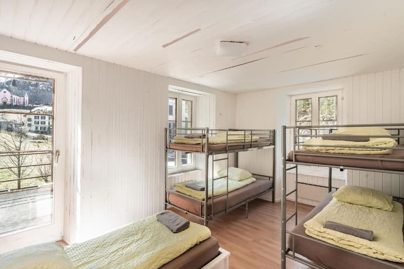 Dormitory room with metal bunk beds and view of alpine village outside window