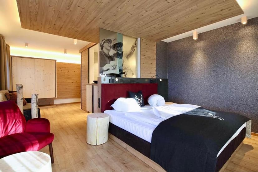 Hotel Stauder bedroom with wood paneling, red seating, and black bedding.