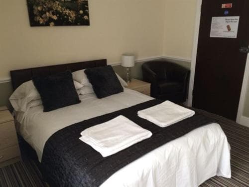 Double bed with white linens, dark throw, and black pillows in a hotel room near Marlow.