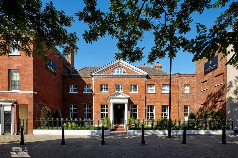Sir Christopher Wren Hotel exterior with red brick facade and green trees under blue sky.