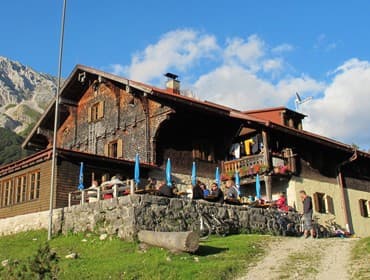 Hallerangerhaus mountain hut with outdoor terrace dining and bicycles parked nearby.