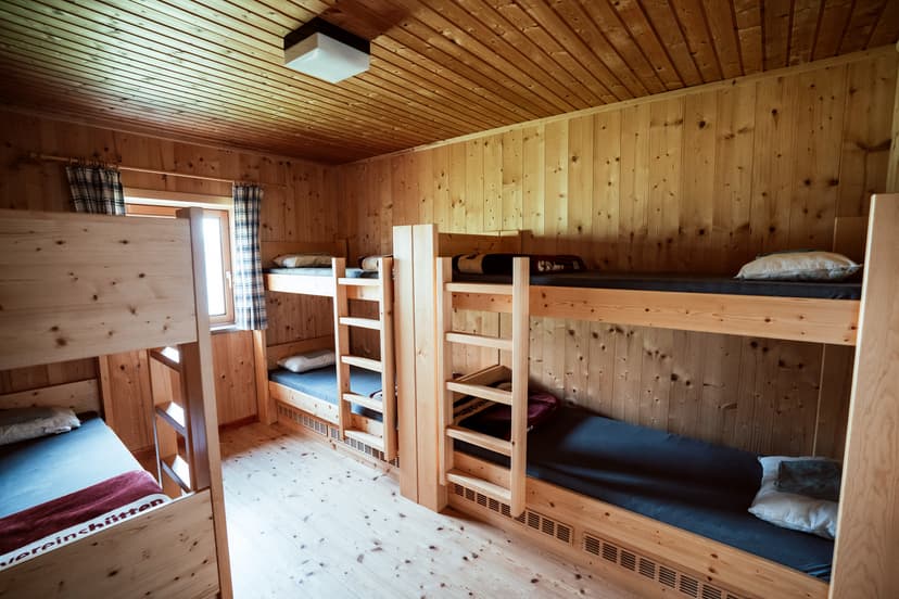 Bunk beds in a wooden room with light wood paneling and a window at Starkenburger Hütte.
