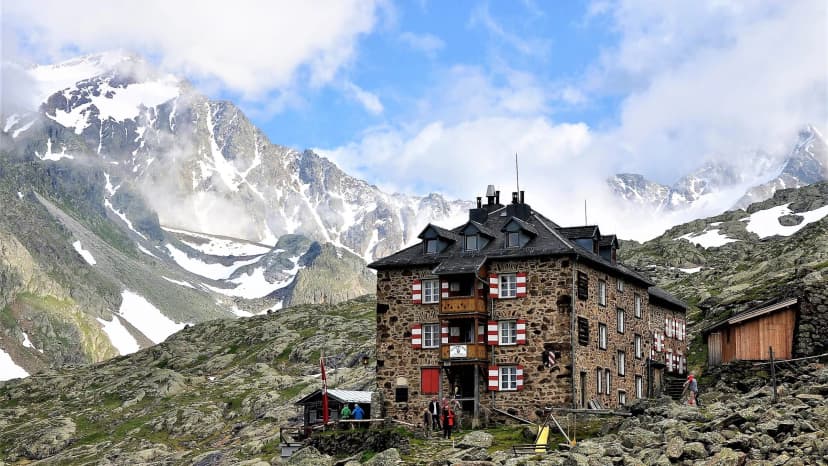 Nürnberger Hütte stone mountain refuge surrounded by snow-capped peaks and rocky terrain.