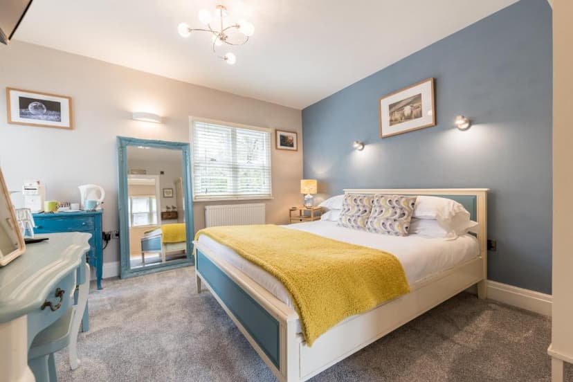 Bedroom in Heidi's Grasmere Lodge with blue accent wall and yellow throw