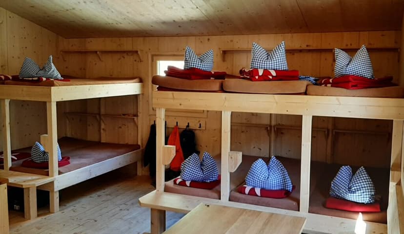 Bunk beds with red blankets and blue gingham pillows inside the wooden Winnebachseehütte.