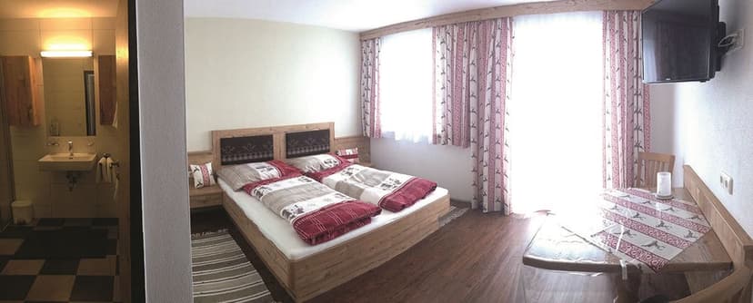 Twin beds in rustic room with wood furniture, patterned linens, and adjacent bathroom.