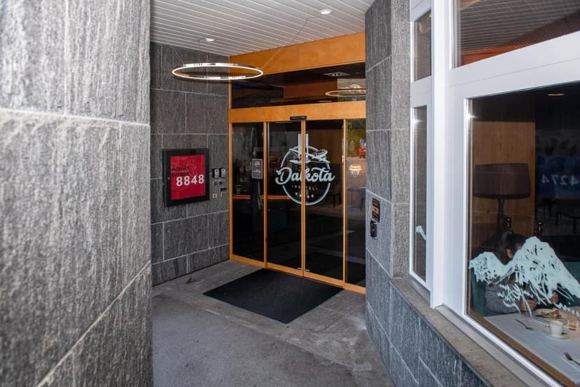 Hotel Dakota entrance with glass doors, gray stone walls, and a Mount Everest sign.