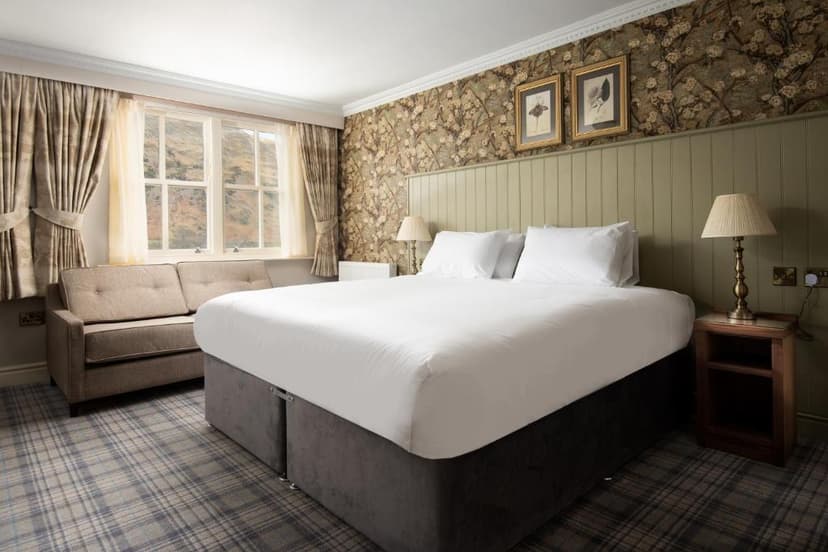 Bedroom with white bedding, plaid carpet, and view of hills through a window at The Ullswater Inn.