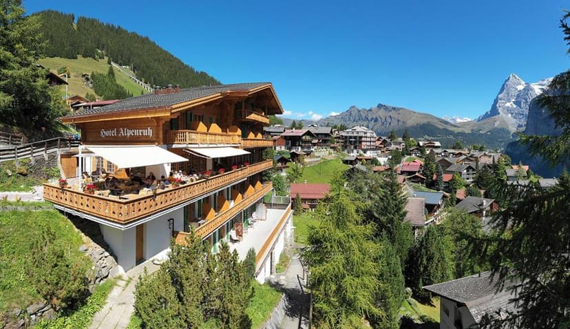 Hotel Alpenruh with wooden balconies overlooking an alpine village and snow-capped mountains.