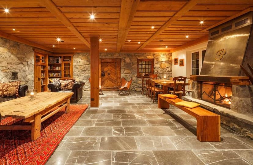 Cozy rustic hotel lounge with stone walls, wood ceiling, large fireplace, and stone floor in Griesalp.