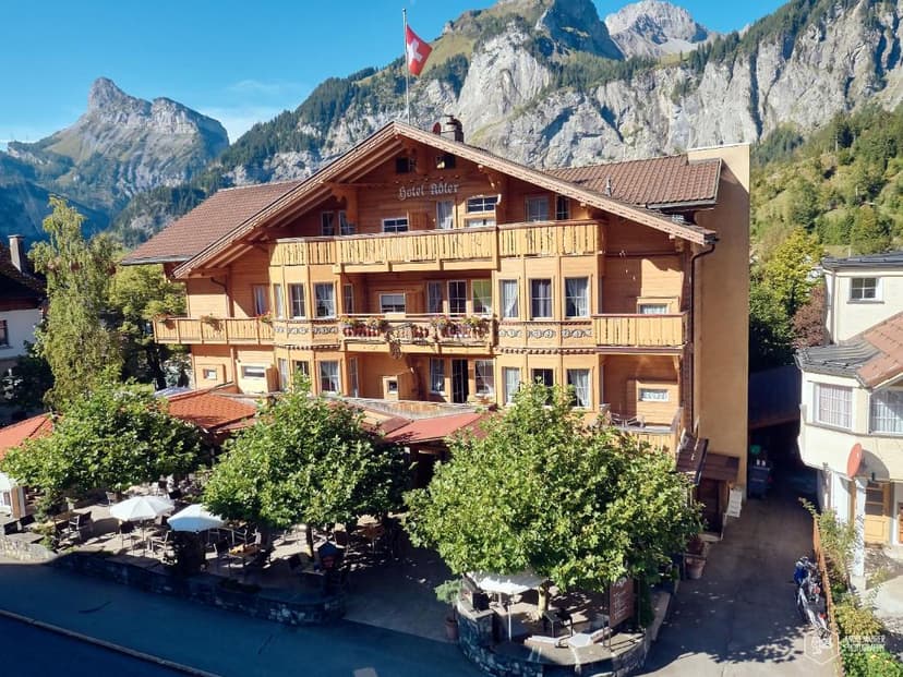 Chalet Hotel Adler with Swiss flag below rugged mountains and outdoor dining area