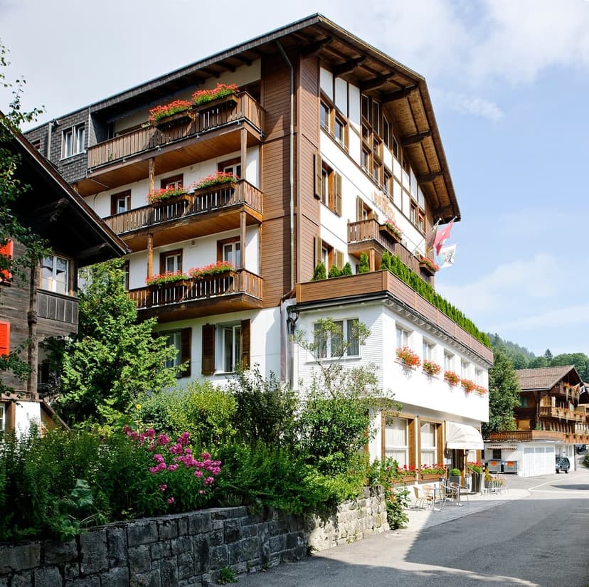 Hotel Bristol Adelboden building with wooden balconies and flower boxes on a sunny day.