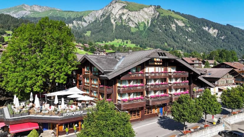 Hotel Kreuz with outdoor terrace dining against a backdrop of lush green mountains.