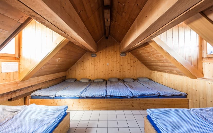 Wooden attic dormitory with bunk beds, blue gingham bedding, and sloped ceilings at Cabane Mont-Fort.
