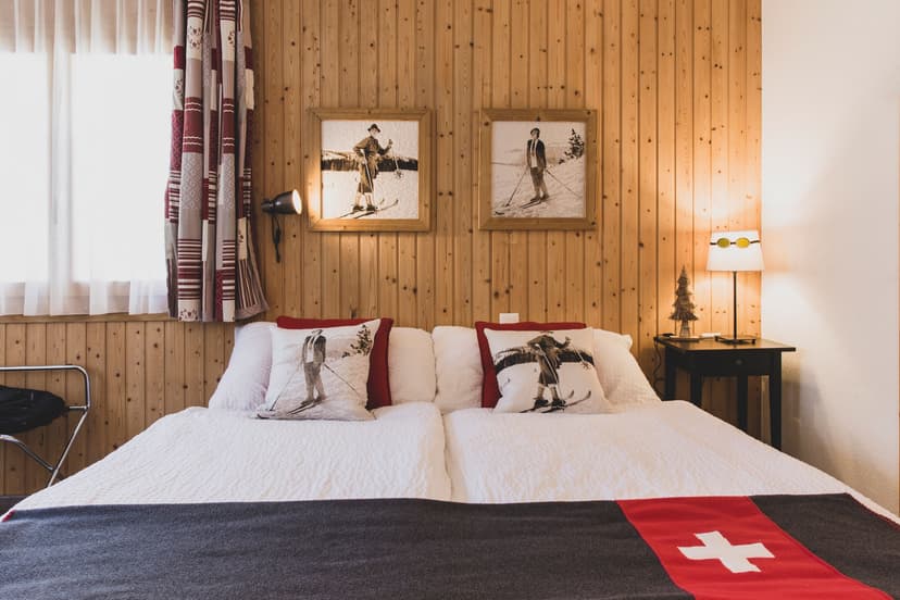 Hotel room with wood paneling, white bedding, and vintage skier photos, Hotel La Pointe de Zinal.