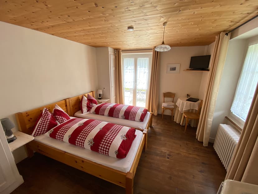 Twin beds with red and white edelweiss bedding in a room with wood ceilings and floors.