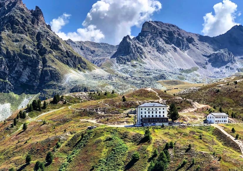 Hotel Weisshorn building nestled on a grassy slope beneath rugged alpine mountains.