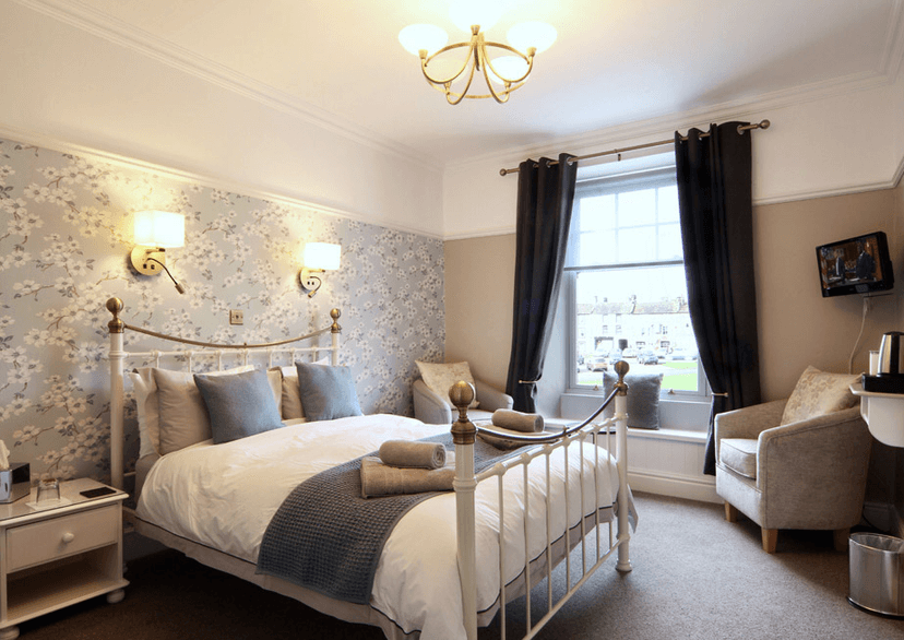 Bedroom in Ivy Cottage Bed & Breakfast with white iron bed and floral wallpaper