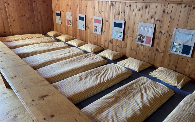 Bunk room with yellow gingham bedding and pillows against wood paneling at Ringelspitzhütte.