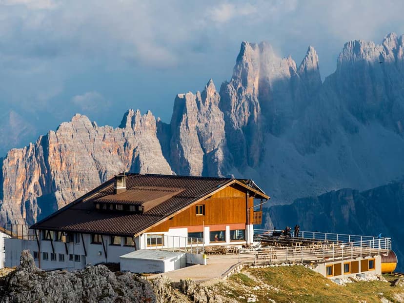 Rifugio Lagazuoi mountain hut with terrace against jagged, rocky peaks in the Dolomites.