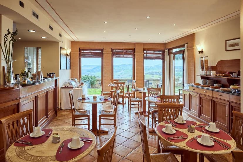 Dining room with wooden furniture and breakfast buffet overlooking rolling green hills.